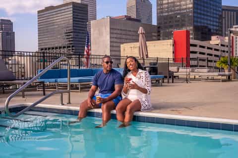 Couple relaxing by rooftop pool with downtown skyline views and summer beverages