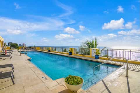Rooftop pool with yellow railings, lounge chairs, and cityscape views