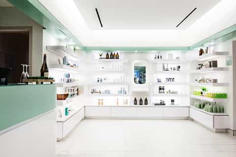 Modern skincare retail shop interior with white shelving displaying beauty products and mint green accents