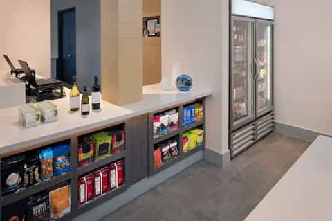 Hotel beverage station with counter, refrigerated display, snacks, and room access door