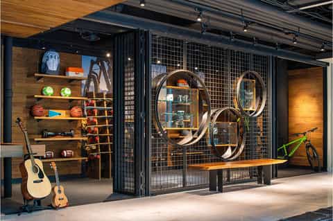Modern sports lounge with guitars, bicycles, and circular mirrors on display shelving