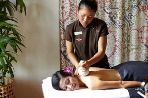 Spa therapist providing shoulder massage to relaxed client on treatment table