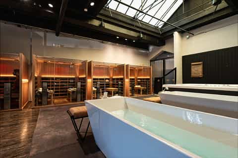 Luxury spa interior with white soaking tubs, wooden lockers, skylights, and minimalist contemporary design