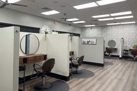 Hair salon station with round mirror, wooden counter, and styled workspace with neutral walls