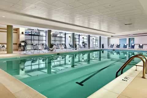 Indoor lap pool with turquoise water and lounge chairs along the side in bright facility