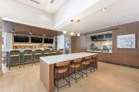 Modern kitchen and bar with wood cabinetry, green tile, and pendant lighting