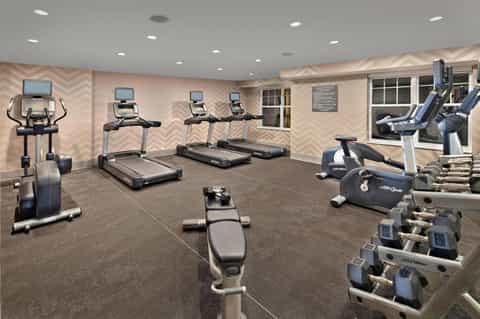 Fitness center with treadmills, exercise bikes, dumbbells, and chevron-patterned accent wall