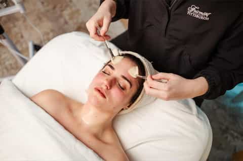 Spa professional providing facial treatment to client wearing headband
