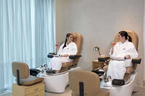 Spa pedicure station with two beige massage chairs and white footbaths facing each other