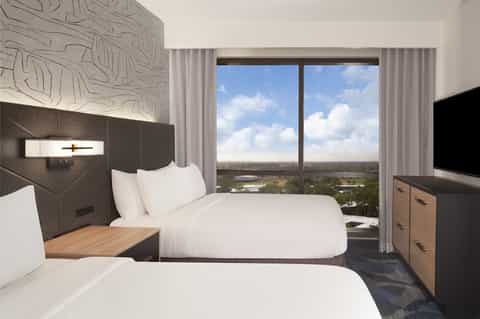 Modern hotel room with two queen beds and expansive window overlooking landscape