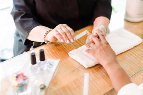 Manicure service with nail polish and jewelry on wooden table