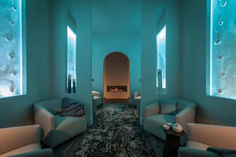 Spa relaxation room with turquoise walls, glowing accent lighting, and fireplace centerpiece