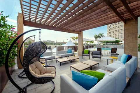 Contemporary rooftop terrace with lounge seating, hanging chair, pergola, and city skyline