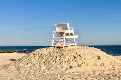 White lifeguard tower on sandy beach with ocean and clear blue sky