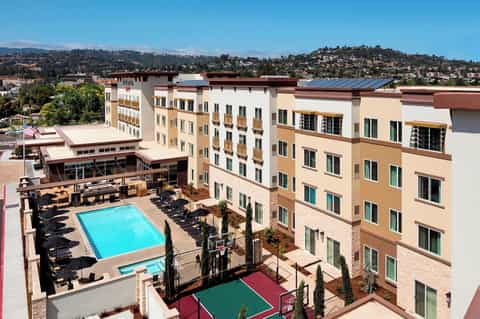 Multi-story resort building with pool, courtyard, and hillside landscape views in background