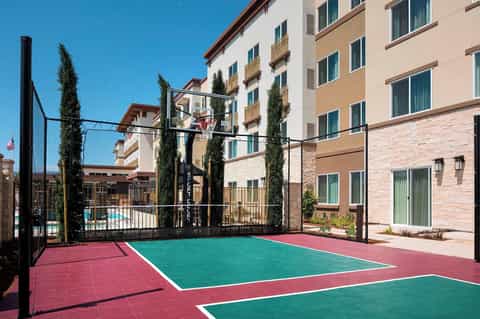 Basketball court at resort with colorful court surface and tall residential buildings