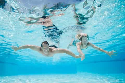 Underwater view of family swimming and snorkeling in crystal-clear resort pool