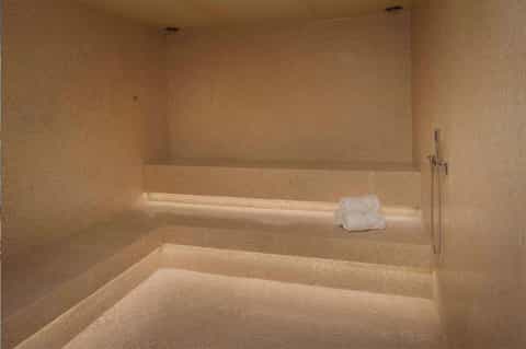 Luxurious spa steam room with golden tile walls, stepped seating, and ambient lighting