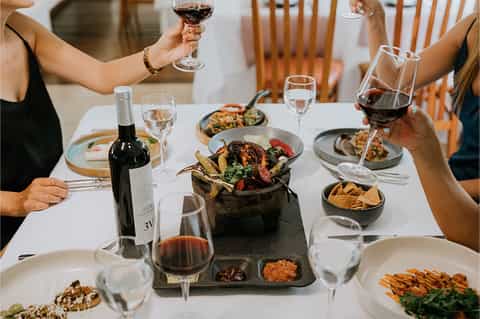 Fine dining table with wine glasses, plated food, wine bottle, and elegant place settings