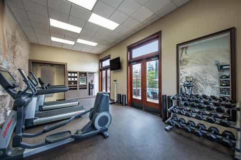 Modern gym interior with treadmills, exercise equipment, windows, and mountain views