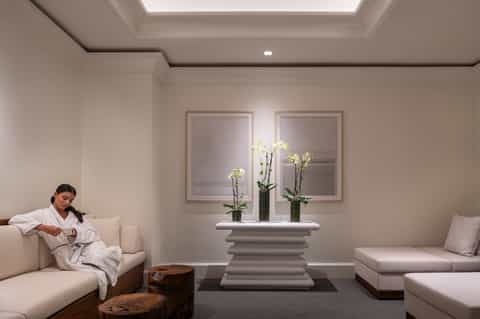 Serene spa relaxation lounge with white furniture, orchid flowers, and minimalist décor