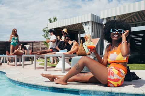 Resort pool party with guests relaxing poolside near modern cabana structure