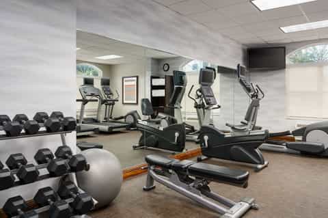Fitness center with cardio equipment, dumbbells and mirrored walls