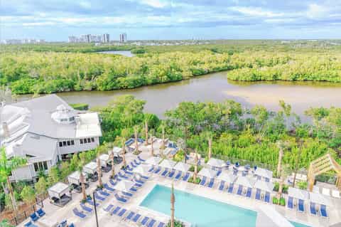 Aerial view of resort pool and deck overlooking mangrove wetlands and distant city skyline