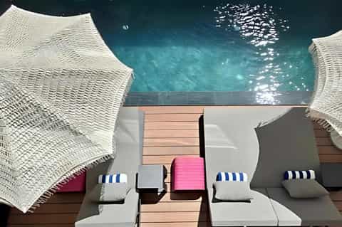 Overhead view of spa relaxation area with white textured lounge chairs, striped cushions, and turquoise water