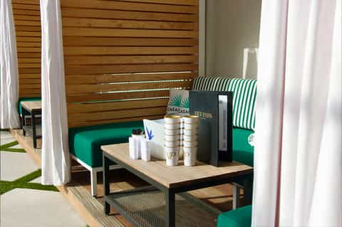 Modern outdoor lounge area with green seating, wood privacy screen, and striped cushions