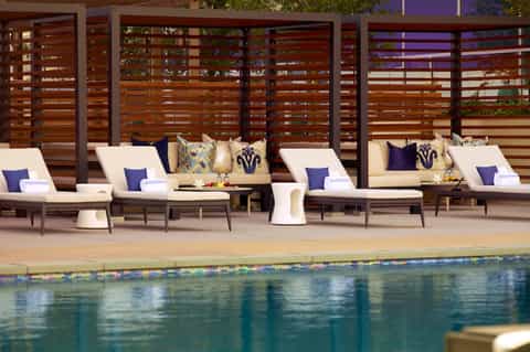 Resort pool lounge area with cream loungers and wooden privacy screens