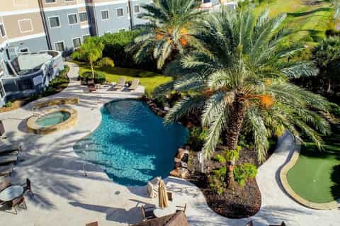 Resort pool area with tropical landscaping, spa, palm trees, and surrounding accommodations