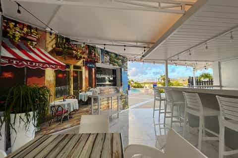 Covered restaurant terrace with views of resort pool and ocean horizon