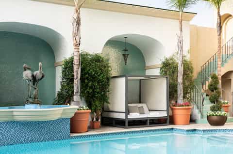 Mediterranean courtyard pool with arched alcoves, turquoise tile, and tropical landscaping