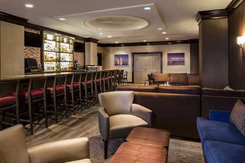 Upscale lounge bar with dark wood, leather seating, and full-service bar setup