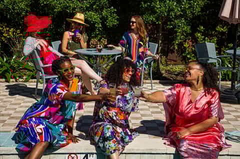 Diverse group celebrating outdoors in bright clothing at resort courtyard with greenery