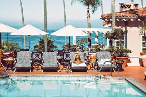 Coastal resort terrace with white umbrellas, lounge chairs, and ocean views