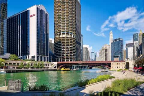 Chicago riverfront view with boats, historic bridge, tall buildings, and riverside seating area