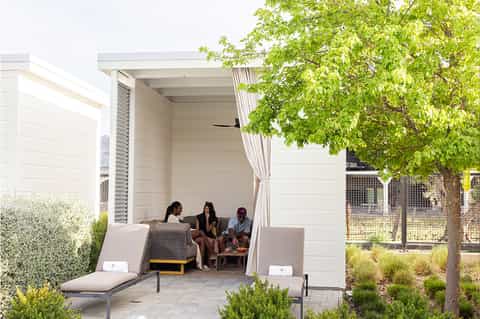 Modern outdoor cabana with white walls, lounge seating, and shaded seating area