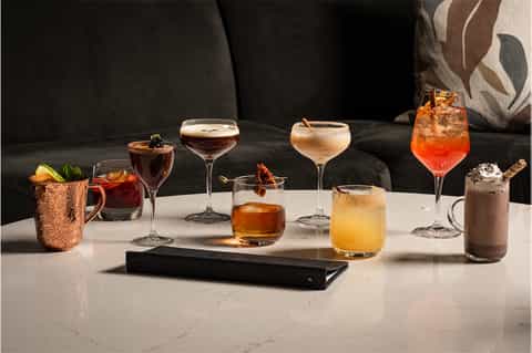Array of colorful cocktails displayed on white marble counter with decorative garnishes