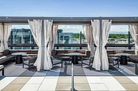Rooftop lounge with white curtained cabanas, black furniture, and mountain landscape views