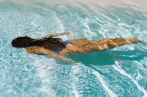 Swimmer doing freestyle stroke in clear turquoise lap pool water