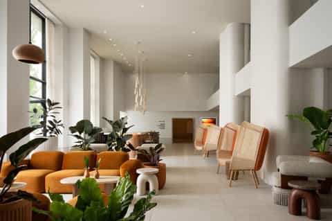 Modern lobby with orange sofa, plant décor, pendant lighting, and contemporary furniture