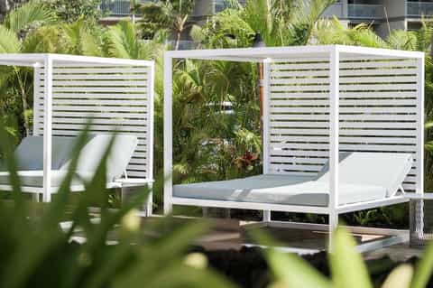 Contemporary outdoor daybed with white canopy surrounded by tropical plants