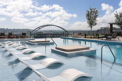 Modern rooftop pool with lounge chairs, spa pool, and city skyline views