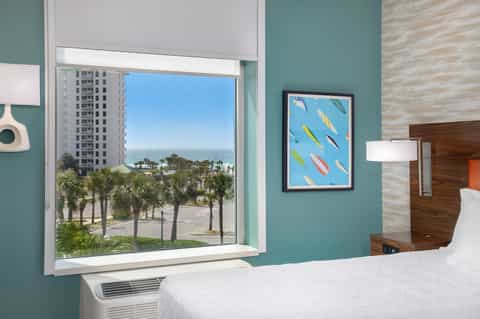 Beachfront hotel room with turquoise walls, ocean view, and palm trees
