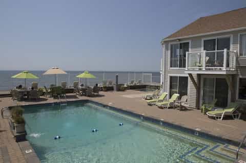 Oceanfront deck with swimming pool, lime-green umbrellas, Adirondack chairs, and ocean view