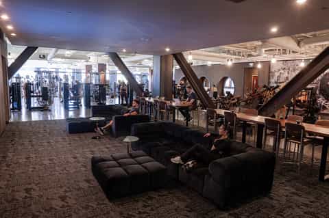 Modern hotel fitness center with gym equipment and seating area with large windows