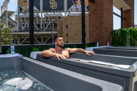Man relaxing in modern hot tub on rooftop with baseball stadium view in background