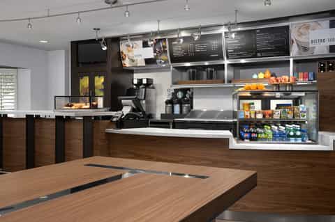 Hotel bistro café interior with counter service, menu boards, pendant lighting, and modern fixtures